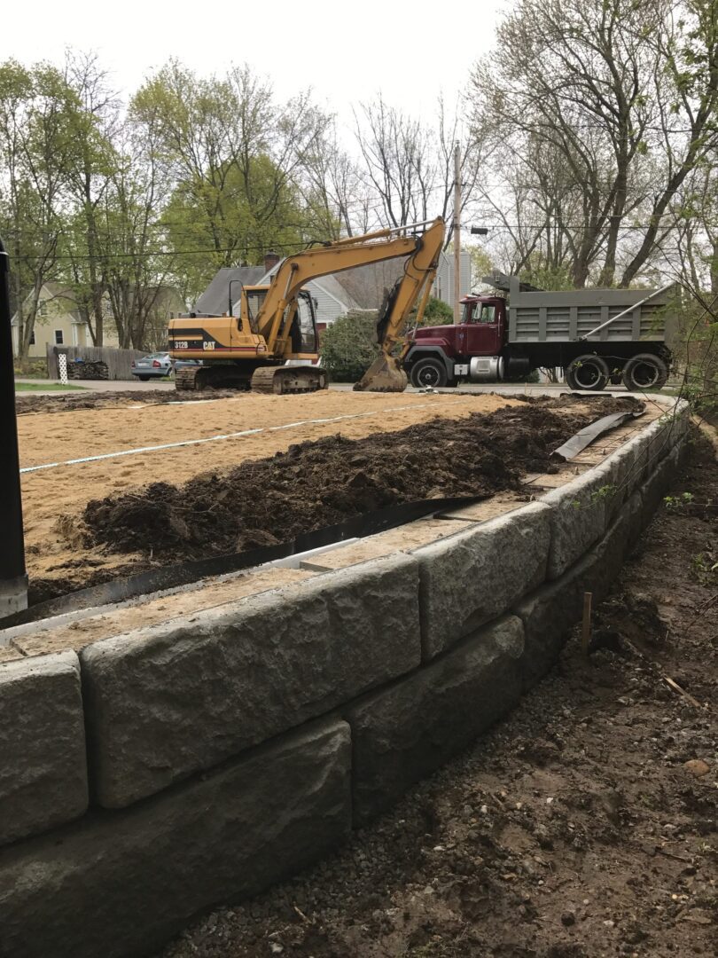 Retaining wall construction site with excavator.