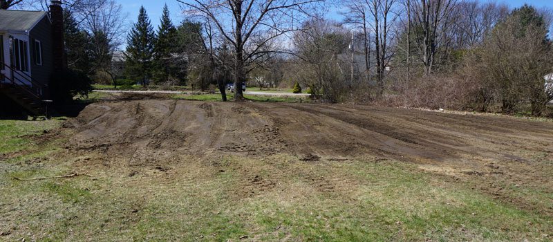 A dirt field with trees in the background