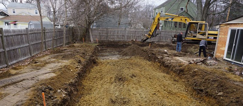 A yellow and black excavator digging in the dirt.