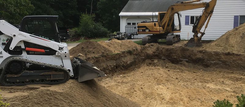 A large pile of dirt with a backhoe in the background.