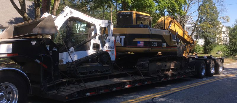 A large truck with two large construction equipment on it.