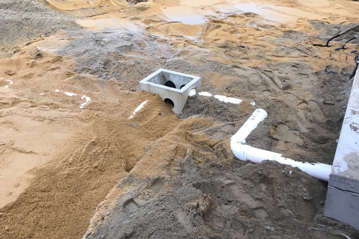A drain and pipe in the sand.
